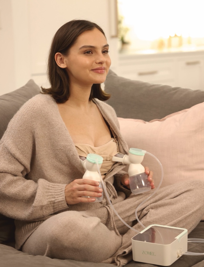 Mom relaxing on the couch while pumping with the Zomee H1 double electric breast pump