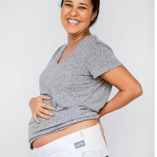 Smiling pregnant mom wearing a white maternity support band